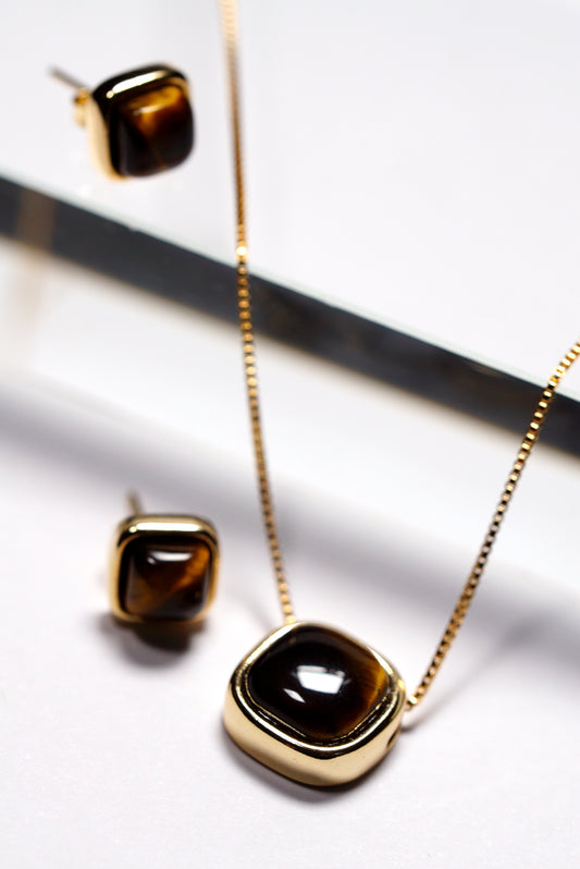 Gold necklace and stud earrings with brown  tiger's eye gemstones on a white background