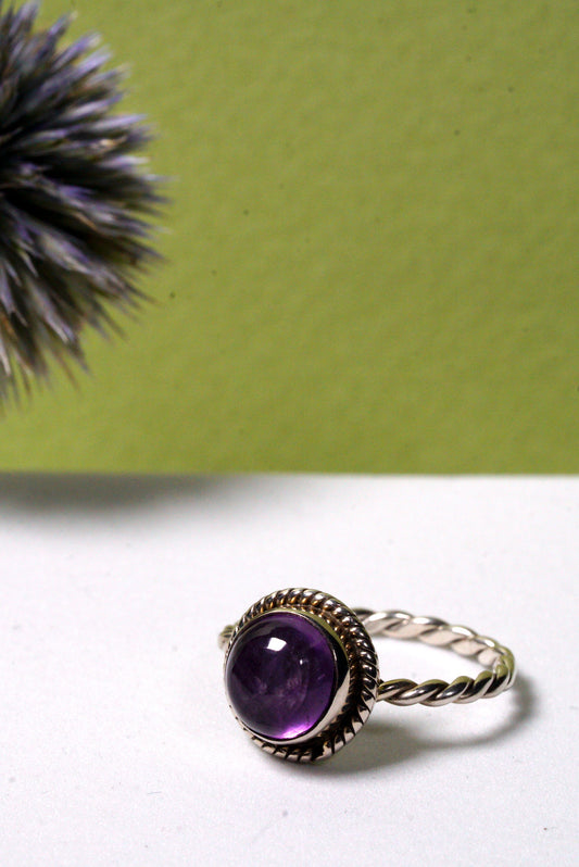 Amethyst Silver ring with a purple gemstone on a white surface with a green background