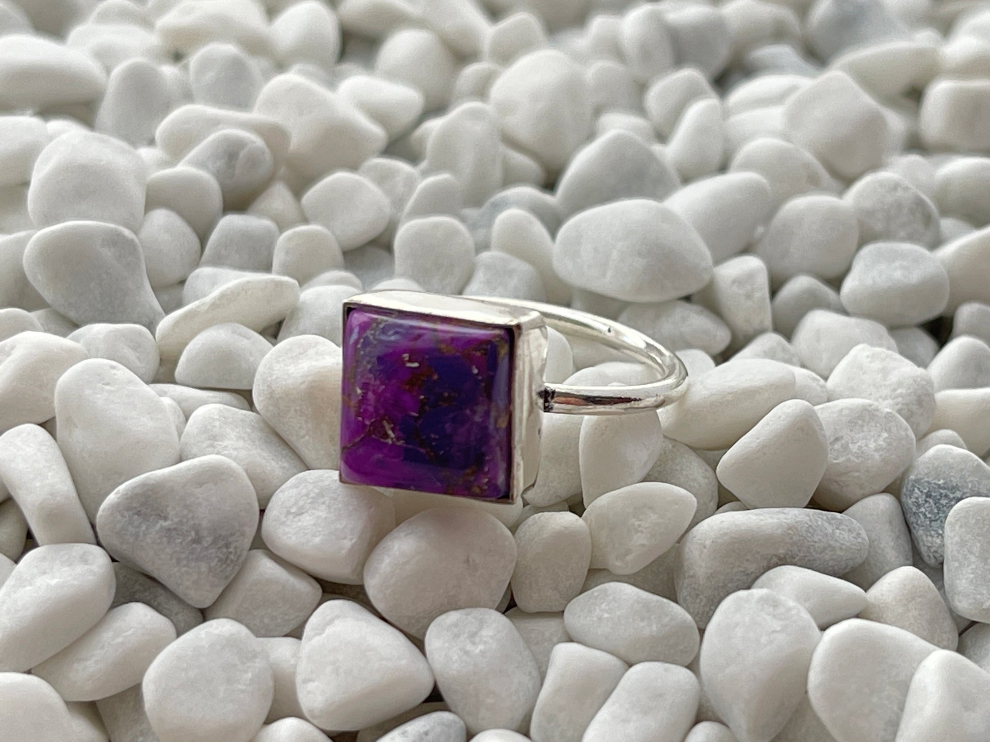 Silver ring with a purple turquoise cooper square stone on white pebbles