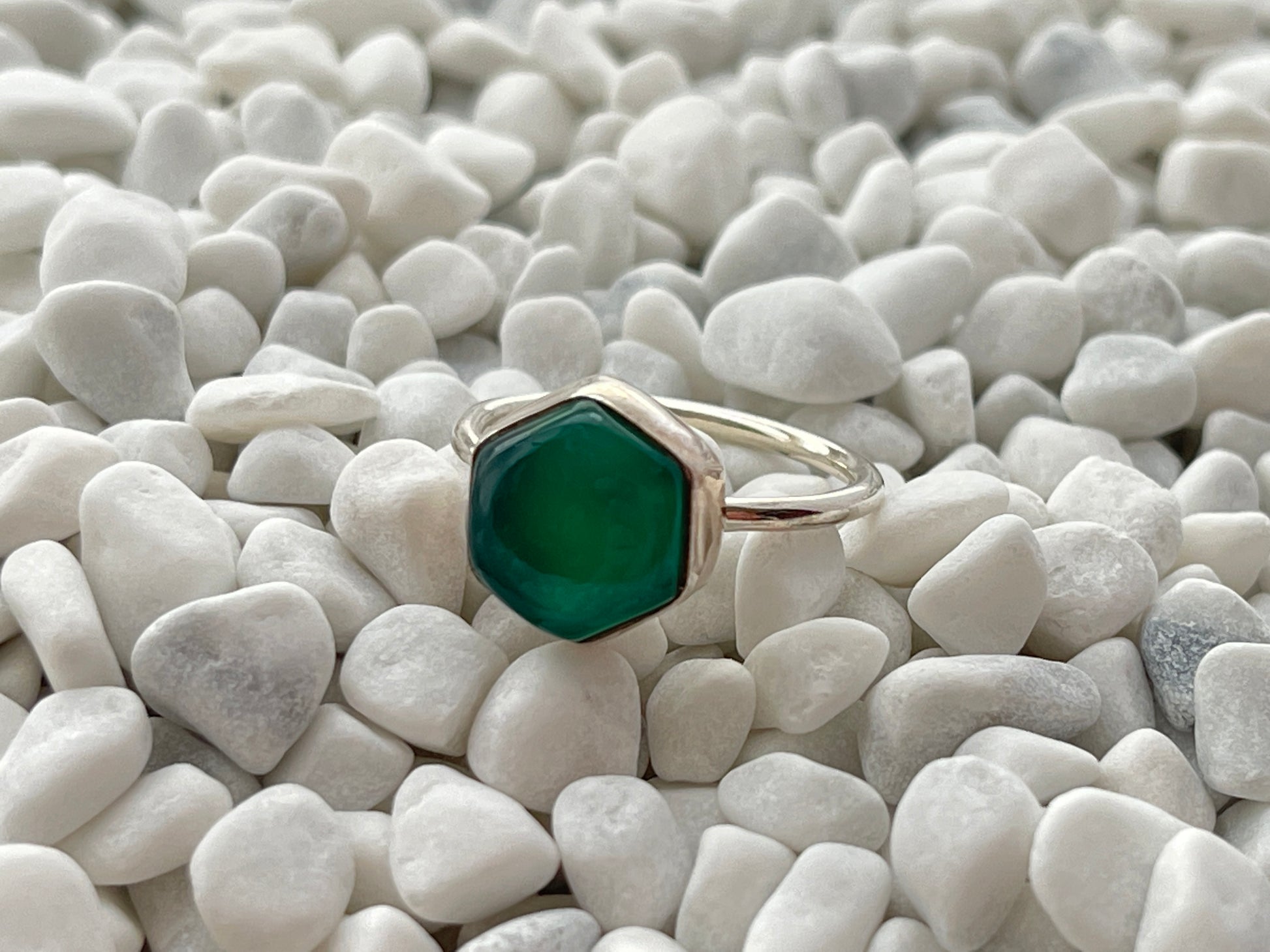Ring with a green onyx gemstone on a bed of white pebbles