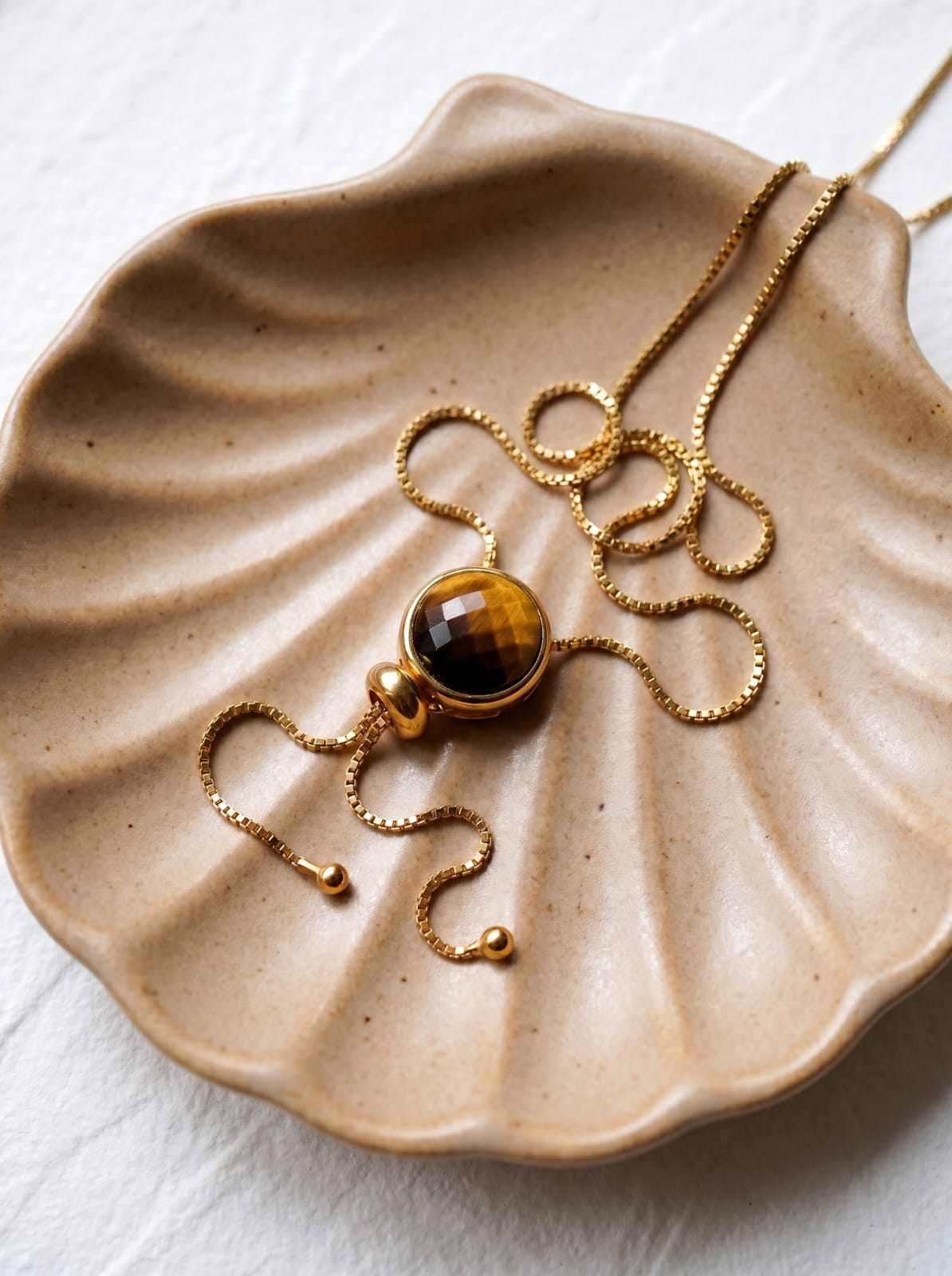 Close-up of genuine tiger's eye pendant showing golden brown chatoyancy on gold-plated lariat