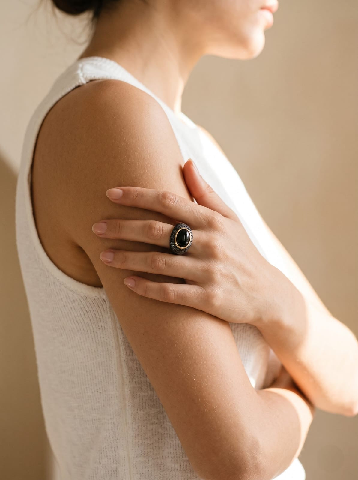 Woman wearing a StoneCraft Jewellery smoky obsidian ring with her hand resting on her upper arm.
