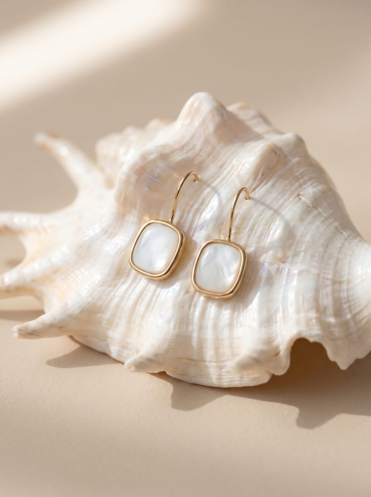 Close-up detail of natural mother of pearl stone in gold-plated rectangle hook earring setting