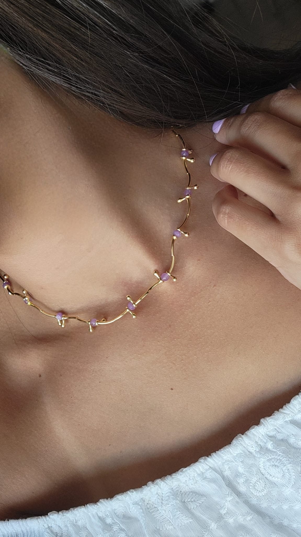 Close-up of a delicate gold necklace worn by a person with a blurred background